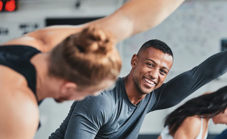 Man smiling alongside another trainer at a gym